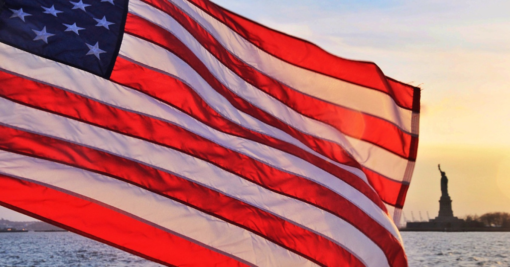 American flag and Statue of Liberty at sunset