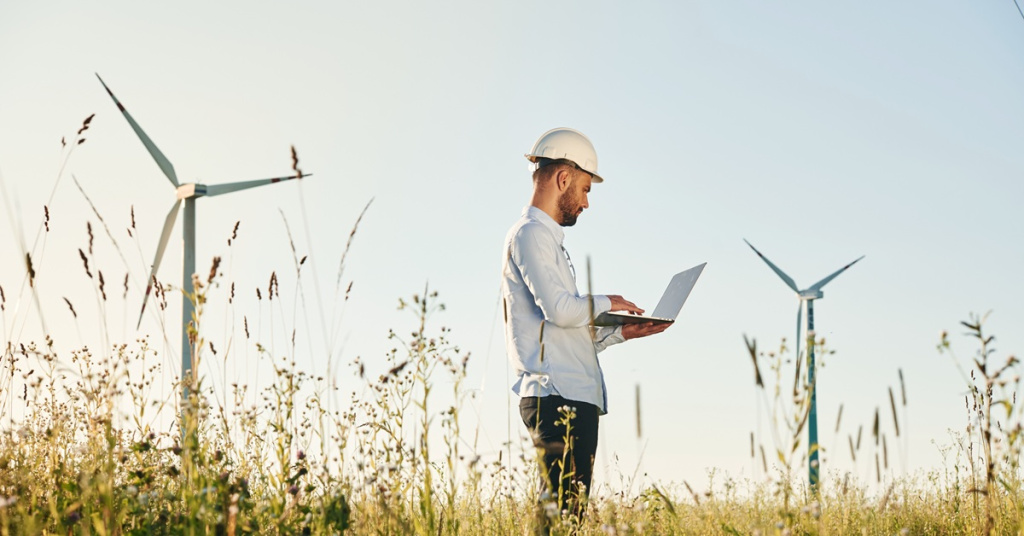 man working on laptop outside near windmills