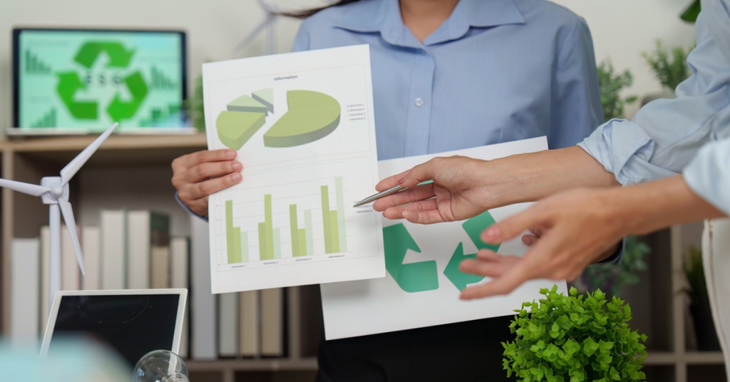 woman holding green charts with sustainability metrics