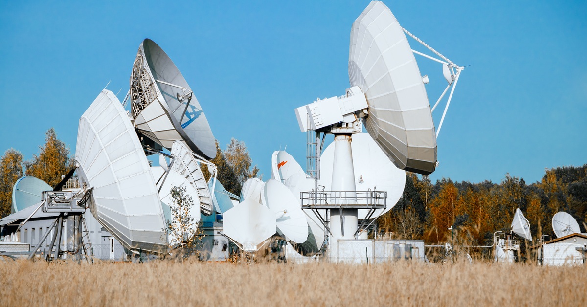 satellite dishes against clear blue sky in field
